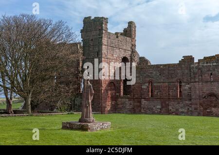 Le rovine del Priorato di Lindisfarne e la statua di San Aidan, Isola Santa, Northumberland, Inghilterra, Regno Unito Foto Stock