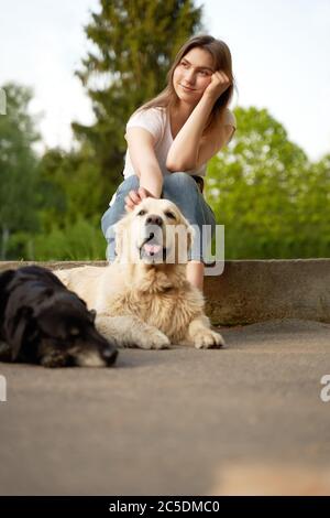 La ragazza pensiva squatting vicino al cane il giorno d'estate. Foto Stock