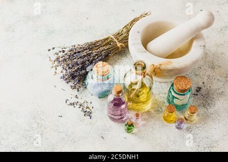 Oli aromatici in bottiglie di vetro, sali aromatici, Malta di marmo e lavanda secca. Concetto naturale ovranico skincare cosmetic. Foto Stock