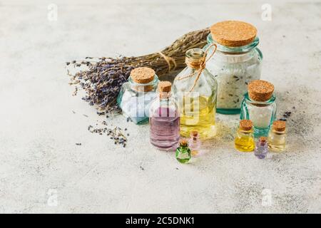 Oli aromatici in bottiglie di vetro, sali aromatici e lavanda secca. Concetto naturale ovranico skincare cosmetic. Foto Stock