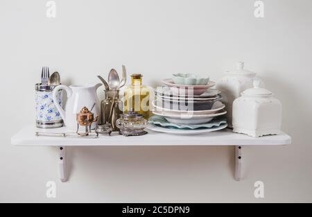 Acquista vecchi vasellame romantico vintage in seconda mano negozio concetto. Pila di preziosi vecchi stoviglie su scaffale per la cucina. Foto Stock