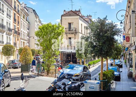 Parigi, Francia - 19 giugno 2015: Auto parcheggiate nelle strette e accoglienti strade della città. Cafe all'angolo di una casa tra alberi verdi Foto Stock