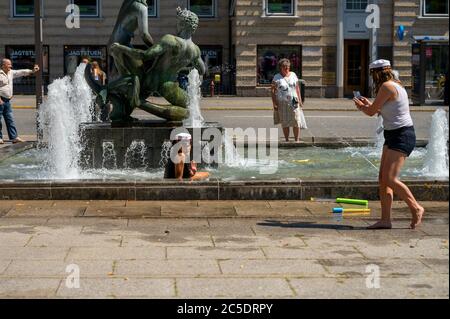Studente danese di scuola superiore con un telefono cellulare scatta una foto di un'altra ragazza in una fontana che celebra la laurea ad Aarhus, Danimarca, il 25 giugno 2020 Foto Stock