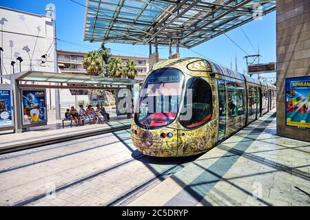 MONTPELLIER, FRANCIA - 24 giugno 2015: Trasporti pubblici urbani. Bellissima tram multicolore. Passeggeri a una fermata del tram. Piattaforma di atterraggio Foto Stock