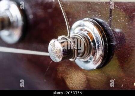 Tasti meccanici per la sintonizzazione della chitarra. Metal Strings UNA chitarra acustica sintonizzata. Lezioni di chitarra. Dettagli cromati dello strumento musicale. Foto Stock