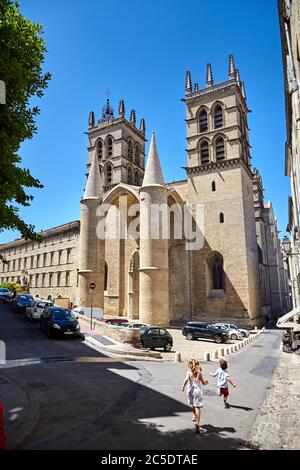 MONTPELLIER, FRANCIA - 24 giugno 2015: Bambini che corrono lungo la vecchia bella strada di fronte alla Cattedrale di San Pietro (Cathédrale Saint-Pierre) Foto Stock