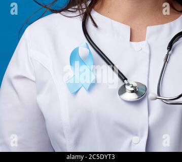 nastro di seta blu attaccato ad un cappotto bianco di un medico. Consapevolezza del cancro della prostata. Concetto di giornata mondiale del cancro Foto Stock