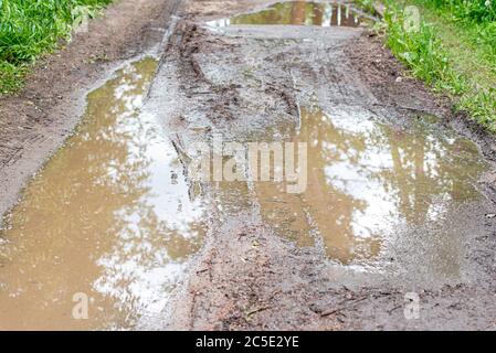 Strada sporca con puddle durante la stagione della pioggia, puddle in strada sterrata Foto Stock