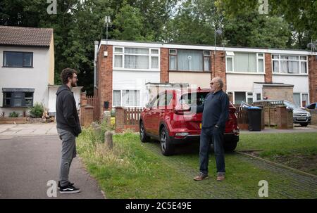 David Blohm (destra) parla con il suo vicino Jack Gutteridge attraverso il confine di blocco sulla Telford Way a Leicester. David Blohm e Jack Gutteridge vivono accanto l'uno all'altro, ma si trovano sui lati opposti del confine dopo che un blocco locale è stato imposto a seguito di un picco nei casi di coronavirus nella città. Foto Stock