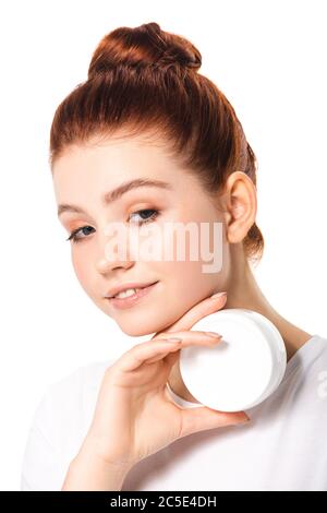 sorridente teen girl che tiene contenitore di plastica con crema cosmetica, isolato su bianco Foto Stock