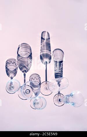 Bicchieri di vino su un tavolo soleggiato gettano ombre, luce del sole, cristalleria, bicchieri di vino, flauto champagne. Foto Stock