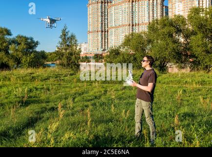 Uomo che aziona un quad copter drone con fotocamera digitale a bordo nel parco cittadino Foto Stock