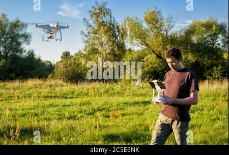 Uomo che aziona un quad copter drone con fotocamera digitale a bordo nel parco Foto Stock