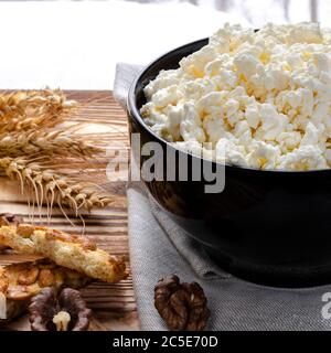 Cibo biologico. La cagliata testurizzata si trova in un piatto nero accanto al miele, dolci fatti in casa e orecchie di grano Foto Stock