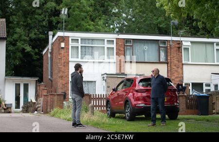 David Blohm (a destra) parla con il suo vicino Jack Gutteridge attraverso il confine di blocco dalla sua casa su Telford Way a Leicester. David Blohm e Jack Gutteridge vivono accanto l'uno all'altro, ma si trovano sui lati opposti del confine dopo che un blocco locale è stato imposto a seguito di un picco nei casi di coronavirus nella città. Foto Stock