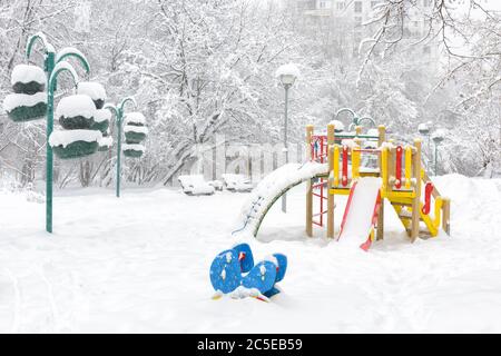 Parco giochi innevato in inverno, Mosca, Russia. Parco urbano vuoto durante la nevicata. Scenario dell'asilo nella città invernale. Foto Stock