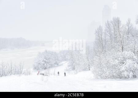 Paesaggio invernale, Mosca, Russia. Durante la nevicata, le persone camminano nel parco vicino al fiume Moskva. Inverno Mosca sfondo esterno. Vista panoramica di una neve Foto Stock