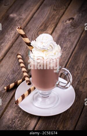 Cioccolata calda con panna montata, in vetro con cialda arrotolata. Elaborazione effetto vintage Foto Stock