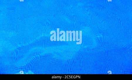 Piscina con fondo di acqua blu pura. Panorama del fondo piscina con motivi piastrellici e superficie ondulata. Vista dall'alto della piscina e del floo distorto Foto Stock