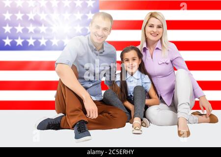 famiglia e concetto di gente - madre sorridente felice, padre e figlia piccola sopra la famiglia della bandiera degli stati uniti Foto Stock