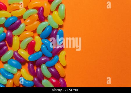 Jelly Beans assortiti bordo con copyspace su sfondo arancione. Foto Stock