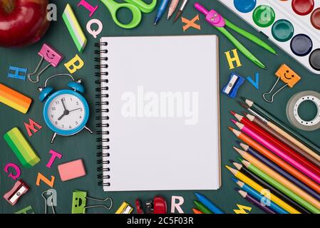 Foto dall'alto del notebook vuoto con cancelleria colorata isolata su una lavagna Foto Stock
