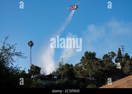 Un elicottero antincendio di emergenza fa cadere l'acqua su un fuoco a spazzola che salva le case in un fuoco selvaggio della California. Foto Stock