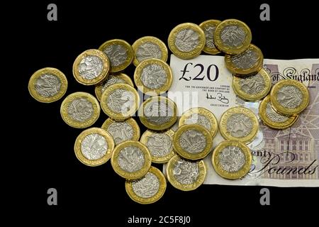 LONDRA, UK - APRILE 2019: Primo piano della valuta britannica GBP - monete da una sterlina e una nota da venti sterline isolate su un fondo nero Foto Stock