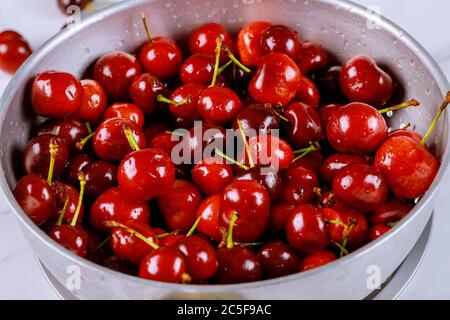 Ciliegie mature prelavate con gambo in colino su tavola bianca. Primo piano. Foto Stock