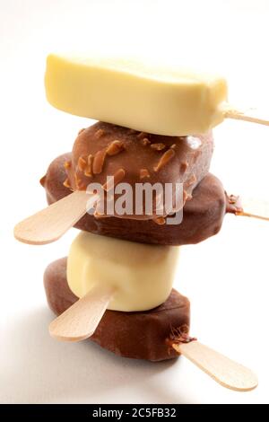 Cibo estivo rinfrescante, dessert ghiacciato e snack surgelati con primo piano su una pila di barrette di gelato dolce rivestite di cioccolato al latte e nocciola Foto Stock