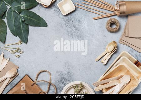 Carta artigianale ecologica e stoviglie in legno. Tazze di carta, piatti, borse, piatti e posate di bambù su sfondo grigio. Riciclaggio o concetto ecocompatibile, Top Foto Stock