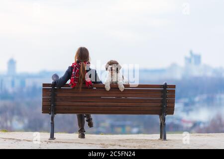 donna e il suo cane seduti sulla panchina del parco Foto Stock