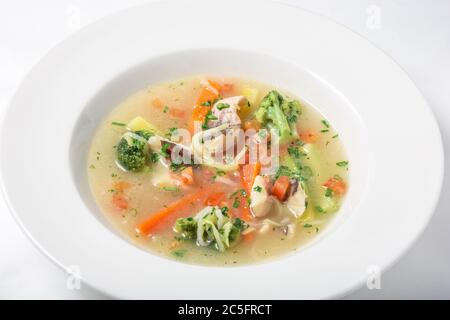 Zuppa di pesce leggera con verdure e broccoli in piatto bianco. Foto Stock