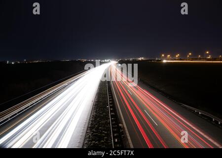 Piste per auto leggere in autostrada che conducono dalle auto di passaggio durante la notte. Foto Stock