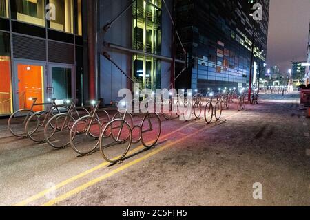 Biciclette nel centro di Oslo Norvegia durante l'inverno, tutte coperte di neve fresca durante la sera Foto Stock