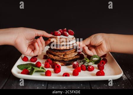Frittelle al cioccolato con lamponi freschi e menta su sfondo nero Foto Stock