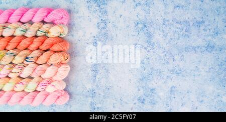 Un bordo di filati rosa su uno sfondo blu puntinato Foto Stock