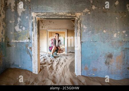 Una donna esplora i resti di un vecchio edificio, Kolmanskop, Karas Regione, Namibia Foto Stock