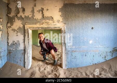 Una donna esplora i resti di un vecchio edificio, Kolmanskop, Karas Regione, Namibia Foto Stock