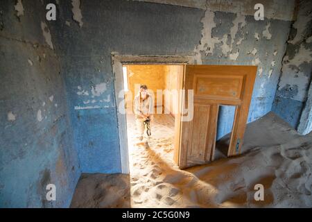 Una donna esplora i resti di un vecchio edificio, Kolmanskop, Karas Regione, Namibia Foto Stock