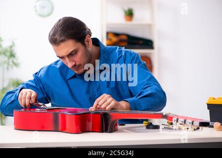 Giovane uomo riparatore riparando la chitarra Foto Stock