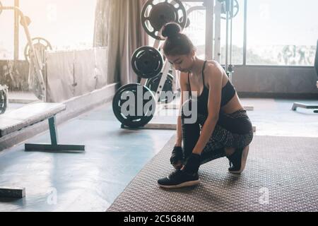 Donna seduta con le mani allacciando scarpe da ginnastica con spazio per la copia. Foto Stock