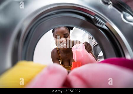 Donna che usa il sapone di riempimento della lavatrice guardando dentro Foto Stock