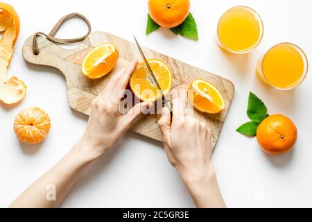 Mani che tagliano gli agrumi per il succo d'arancia Foto Stock