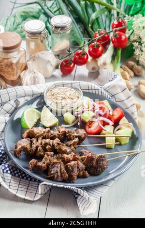 Tradizionale satay di maiale con salsa di arachidi e verdure. Indonesiano e malese. Foto Stock