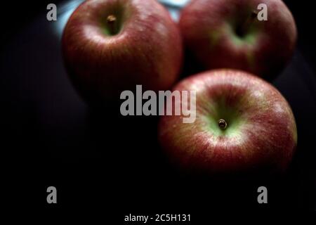 Un gruppo di tre mele Braeburn in Moody Light Foto Stock