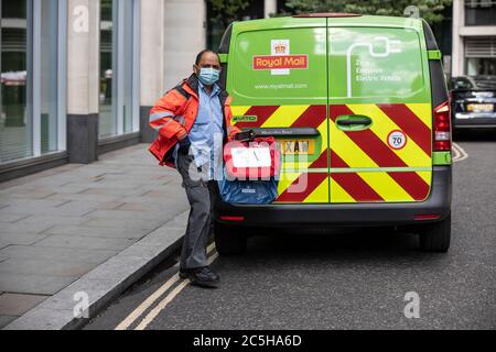 Postal Deliver worker preparandosi a caricare il suo Royal Mail Zero Emission Electric Postal Van indossando una maschera facciale nel centro di Londra, Inghilterra, Regno Unito Foto Stock