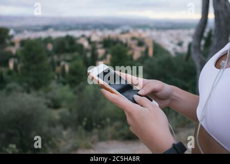 Mani di una ragazza giovane che usa il telefono in natura dopo l'esercizio. Ritagliare una donna irriconoscibile utilizzando l'app di tracciamento mobile mentre si pratica all'aperto. Foto Stock