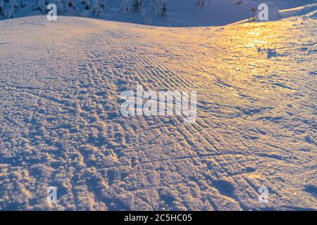 Piste innevate curate con tracce di sci e snowboard in piena giornata invernale Foto Stock