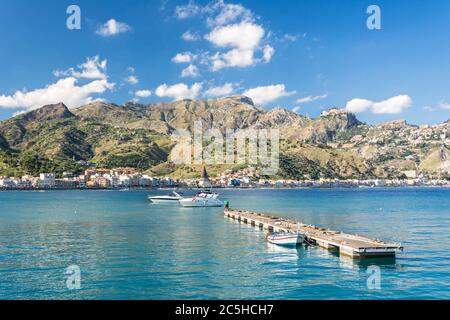 Molo in legno e alcune barche in splendida baia con montagne sullo sfondo dell'isola Sicilia in Italia Foto Stock